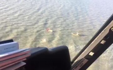 A Coast Guard rescue swimmer from Air Station San Francisco swims to a capsized boat before the air crew hoisted the three stranded mariners near Menlo Park, Calif., July 15, 2017. U.S. Coast Guard video.