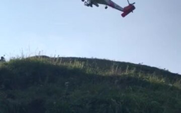 An MH-60 Jayhawk helicopter crew from Coast Guard Air Station Kodiak hoists an injured hiker from North Sister Mountain on Kodiak Island, Alaska, July 11, 2019. The 55-year-old woman reportedly fractured her leg while hiking and was unable to traverse the steep terrain back down the mountain. U.S. Coast Guard video by Petty Officer 1st Class Nadia Laub.