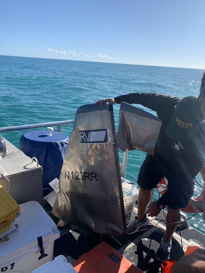 A Monroe County Sheriff's Office diver holds a piece of aircraft debris from the ocean floor 15 miles north of Big Pine Key, Florida, March 3, 2021. Coast Guard crews suspended the search March 3, 2021. (U.S. Coast Guard photo by Station Key West)