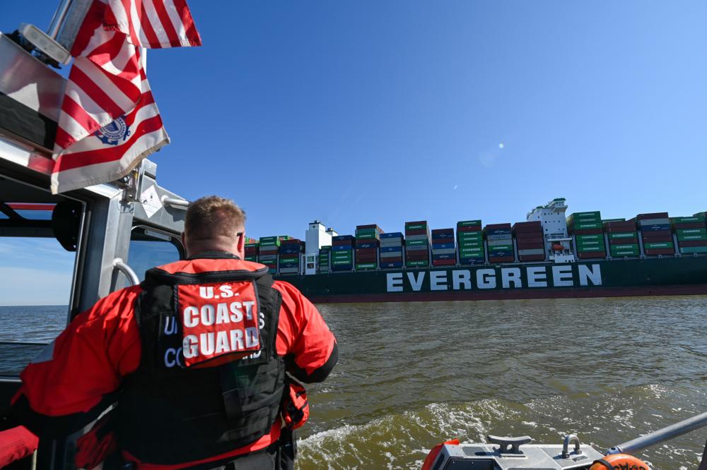 A response boatcrew from Coast Guard Station Curtis Bay monitors the 1,095-foot motor vessel Ever Forward, which became grounded in the Chesapeake Bay, March 13, 2022. The Coast Guard and Maryland Department of the Environment are coordinating the refloating of the container ship. (U.S. Coast Guard photo by Petty Officer 3rd Class Kimberly Reaves/Released)