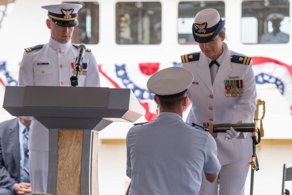 Lt. Lindsey Neumann, the grandniece of the cutter's namesake is Boatswain's Mate 1st Class Clarence Sutphin Jr. presents the long glass to set the first watch and honors his service at the ship's commissioning ceremony in New York City, on April 21, 2022. 