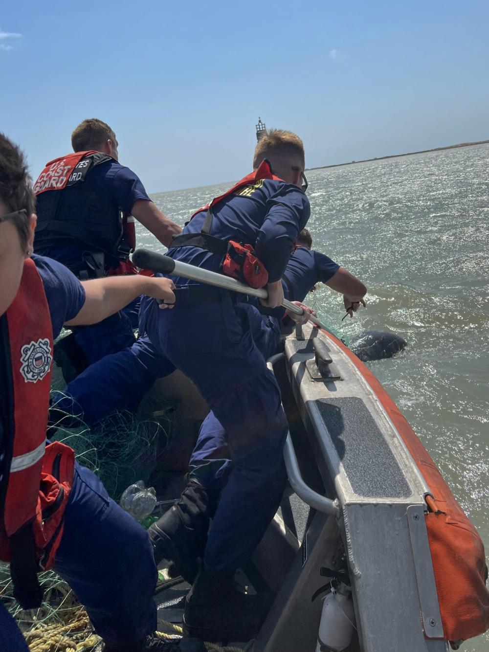 A Coast Guard Station South Padre Island boat crew cuts a dolphin free from illegal fishing nets near South Padre Island, Texas, May 4, 2022. After receiving a call from a boater about the entangled dolphin a Station South Padre Island 24-foot Special Purpose Craft-Shallow Water boat crew launched to respond. The crew freed the dolphin and removed the illegal fishing gear from the water. (U.S. Coast Guard photo by Seaman Lacie Kraatz)
