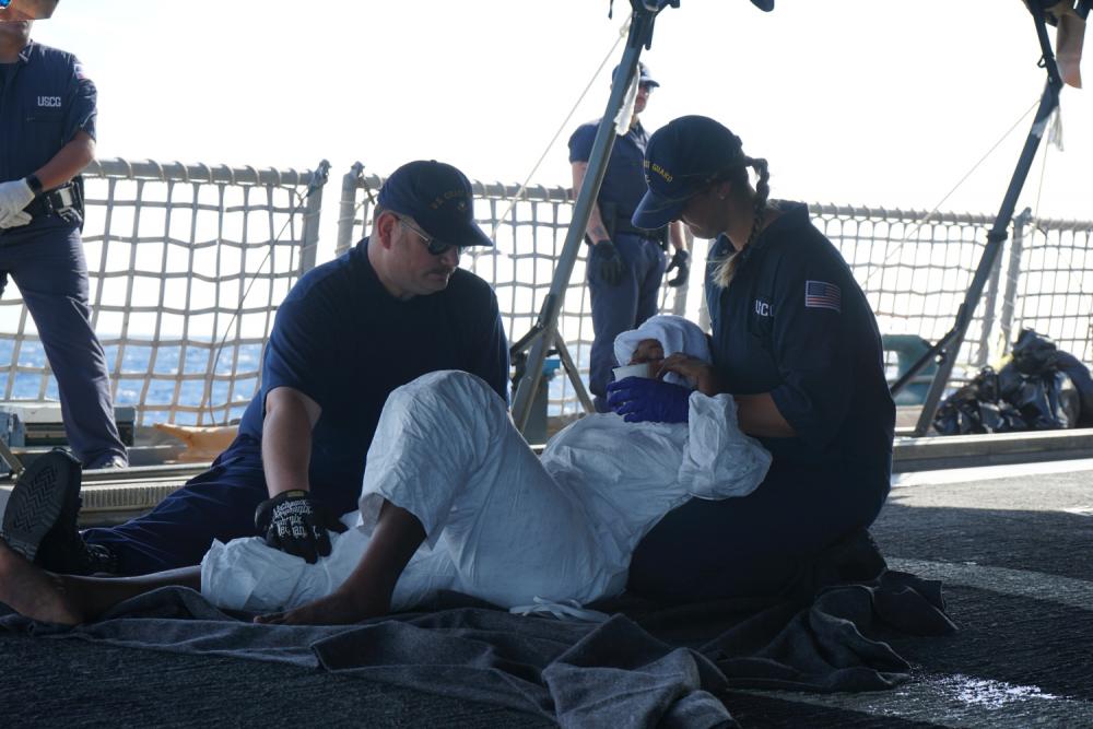 Two Coast Guard Cutter Campbell crew members assist a person suffering dehydration symptoms in the Windward Passage, April 30, 2022. Coast Guard Cutter Campbell is homeported in Kittery, Maine. (U.S. Coast Guard photo by Campbell's crew)