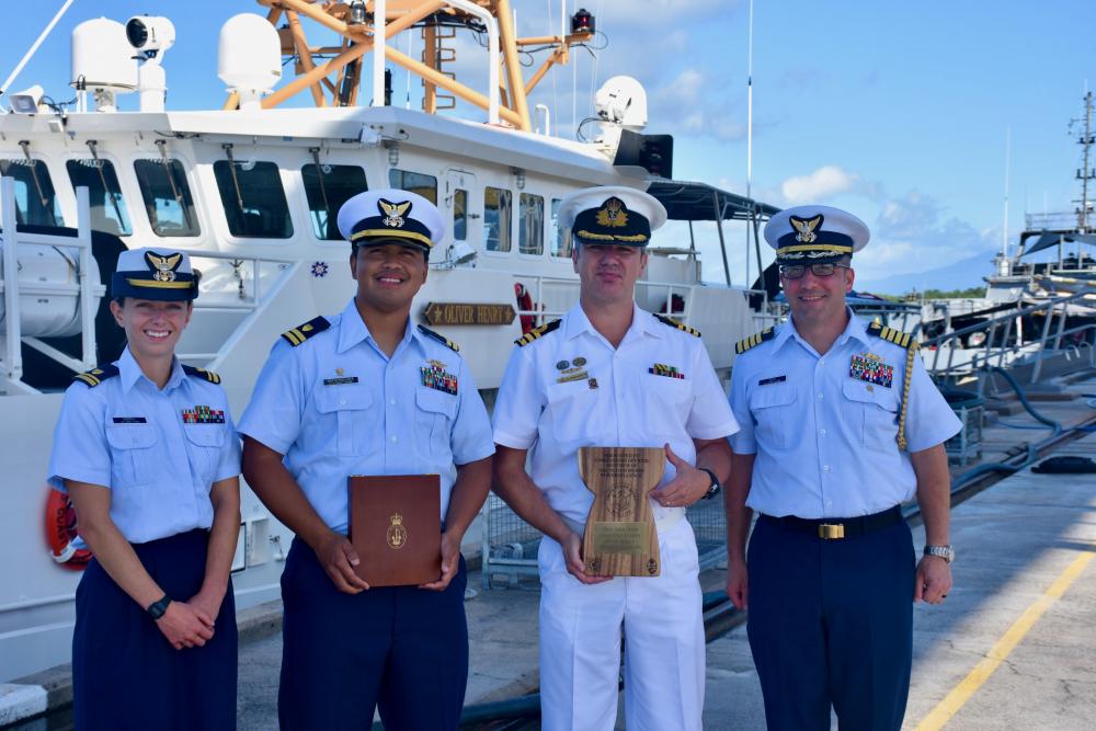 The Sentinel-class fast response cutter USCGC Oliver Henry (WPC 1140) command stand for a photo with Cmdr. Alfonso Santos, commander of HMAS Cairns, and Capt. Toby Reid, U.S. Coast Guard representative to the defense attache office of the U.S. Embassy in Australia,