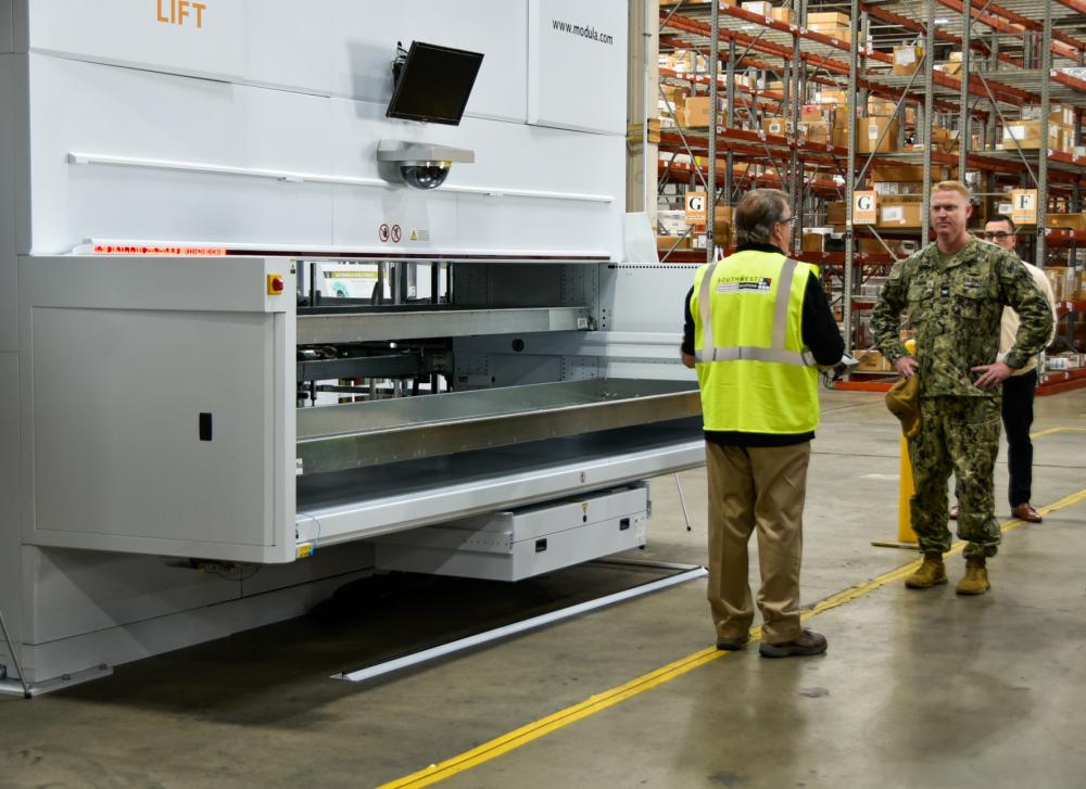 Capt. Cory Schemm, commanding officer NAVSUP FLC San Diego, speaks with Modula employee about the Vertical Lift Module.