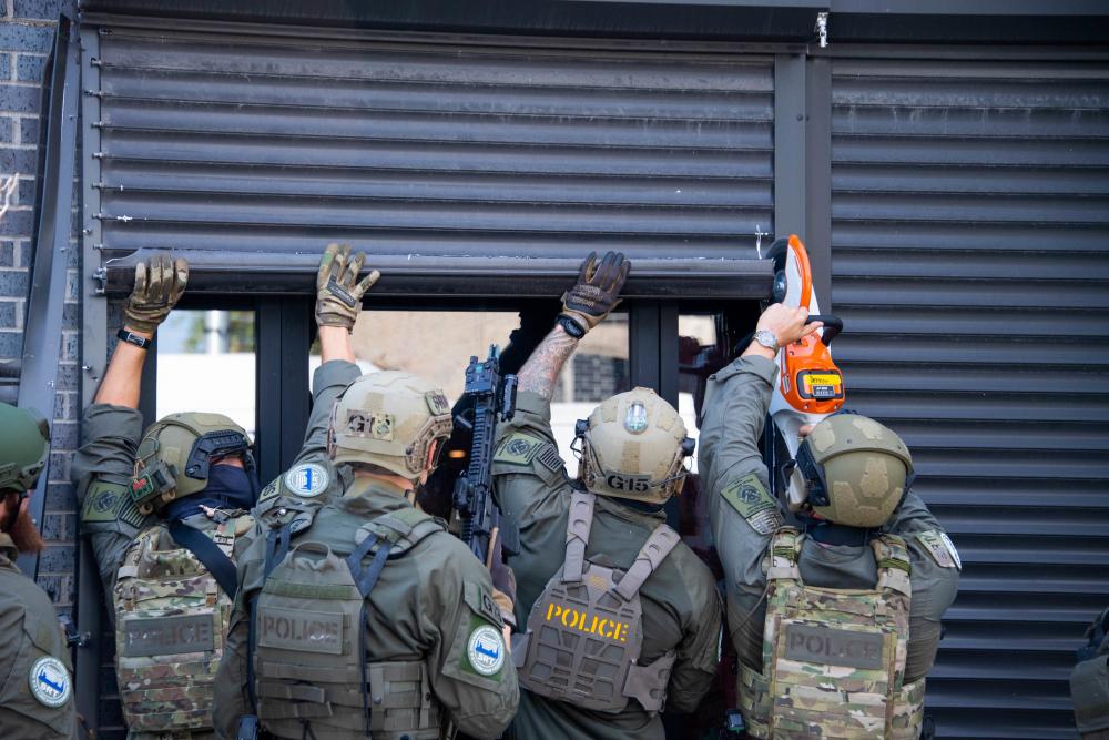 A Special Response Team (SRT) from Homeland Security Investigations (HSI) cuts  open a security door while serving a warrant as part of Operation Boiling Point