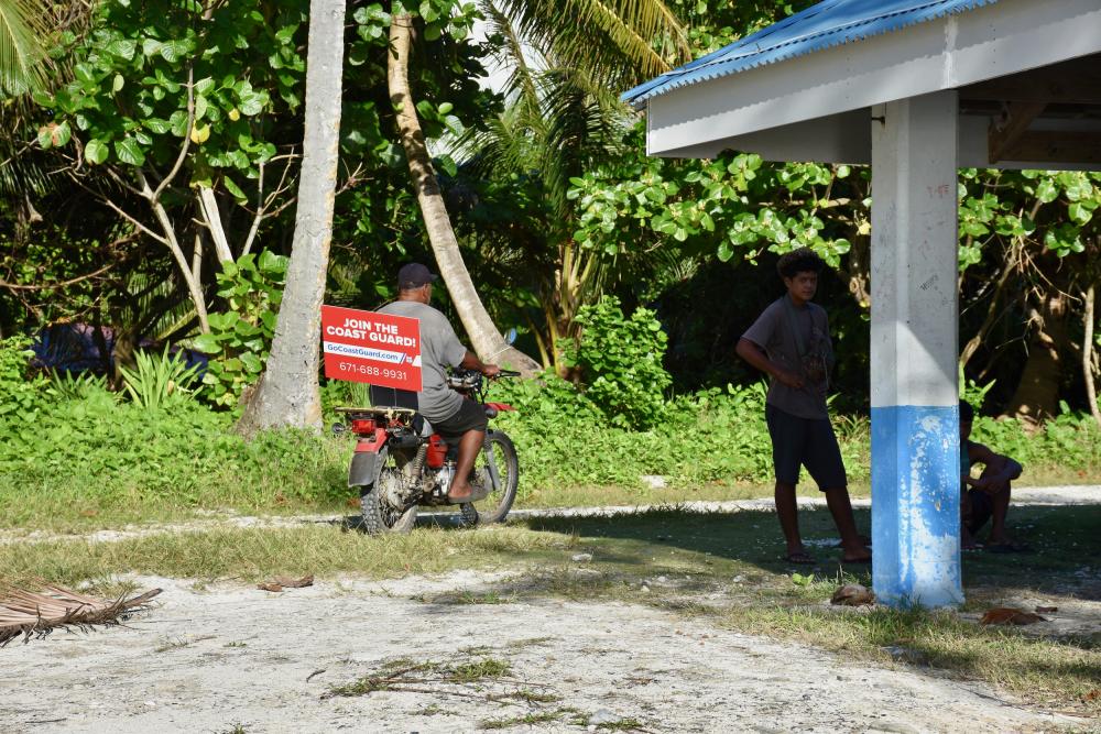 A Ulithi Atoll resident departs the beach with a Go Coast Guard sign