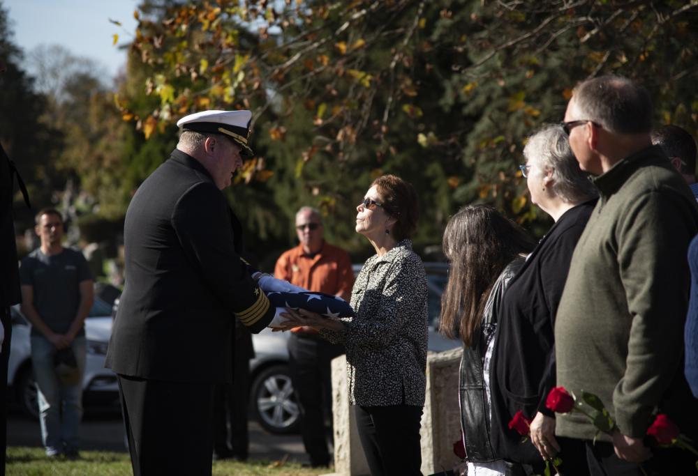U.S. Navy Captain Pete Moore presents the National Ensign to the family of Radioman 3rd Class Charles Montgomery