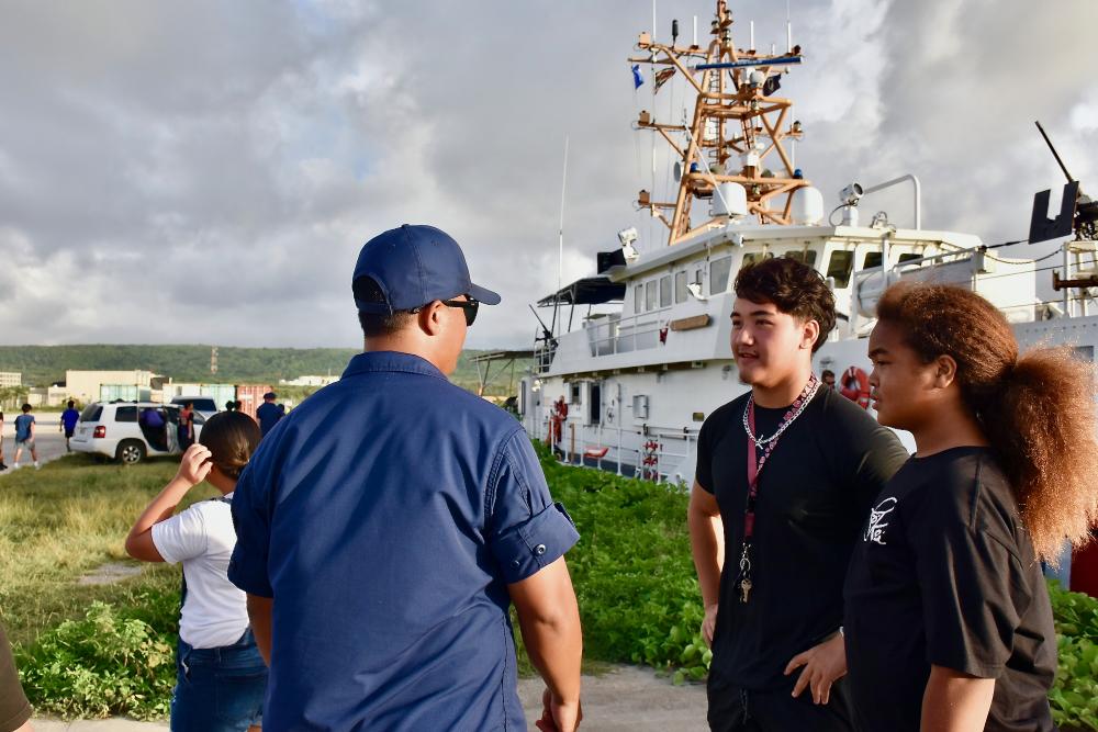 Lt. Freddy Hofscneider, commanding officer of USCGC Oliver Henry (WPC 1140), talks with students from the Tinian Typhoons Sports Association