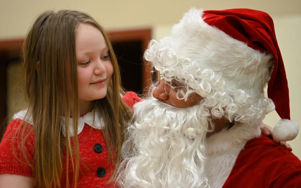 Santa talks to Chloe Stone of Chiniak, Alaska, at the Chiniak School during the Coast Guard-sponsored Santa to the Villages event, Dec. 6, 2022. Kodiak-based Coast Guard personnel have been bringing Santa to the remote villages of Kodiak Island every December for 46 years. U.S. Coast Guard photo by Petty Officer 3rd Class Ian Gray.