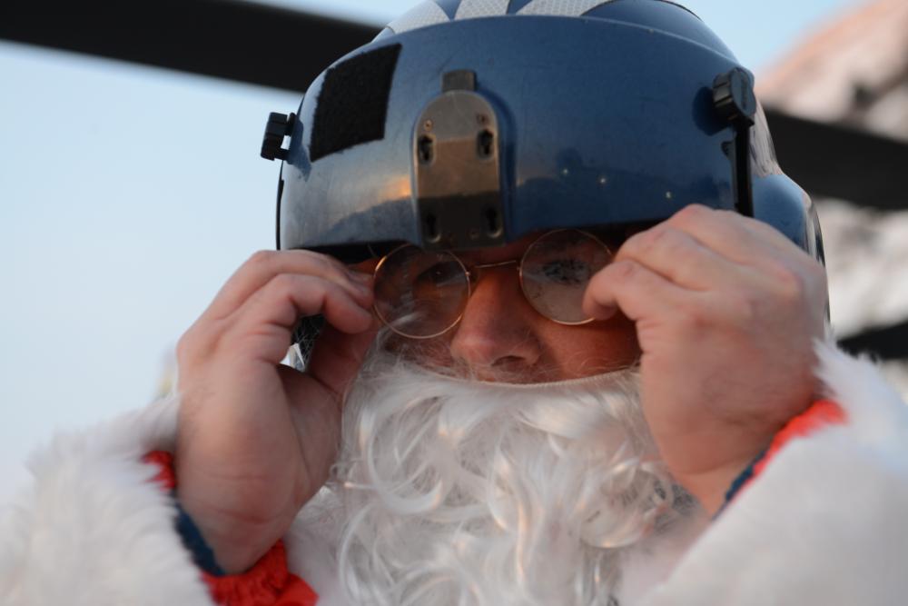 U.S. Coast Guard Chief Petty Officer Bradley Hansen, an informations systems technician stationed at Base Kodiak, fixes his Santa Claus costume glasses after putting on his flight helmet, Nov. 30, 2022. An Air Station Kodiak aircrew flew to the remote village in support of the annual Santa to the Villages program, which has been coordinated for 46 years. U.S. Coast Guard photo by Petty Officer 1st Class Ali Blackburn.