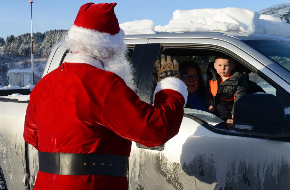 Dressed as Santa Claus, U.S. Coast Guard Petty Officer 1st Class Jason Flynt, an Aviation Survival Technician at Air Station Kodiak, waves to a young child in Port Lions, Alaska, during a visit to the remote village on Nov. 30, 2022. Flynt was one of six Santas that dressed up and flew with the air station crews to deliver presents and visit with the children in the seven remote villages of Kodiak Island. U.S. Coast Guard photo by Petty Officer 1st Class Ali Blackburn.