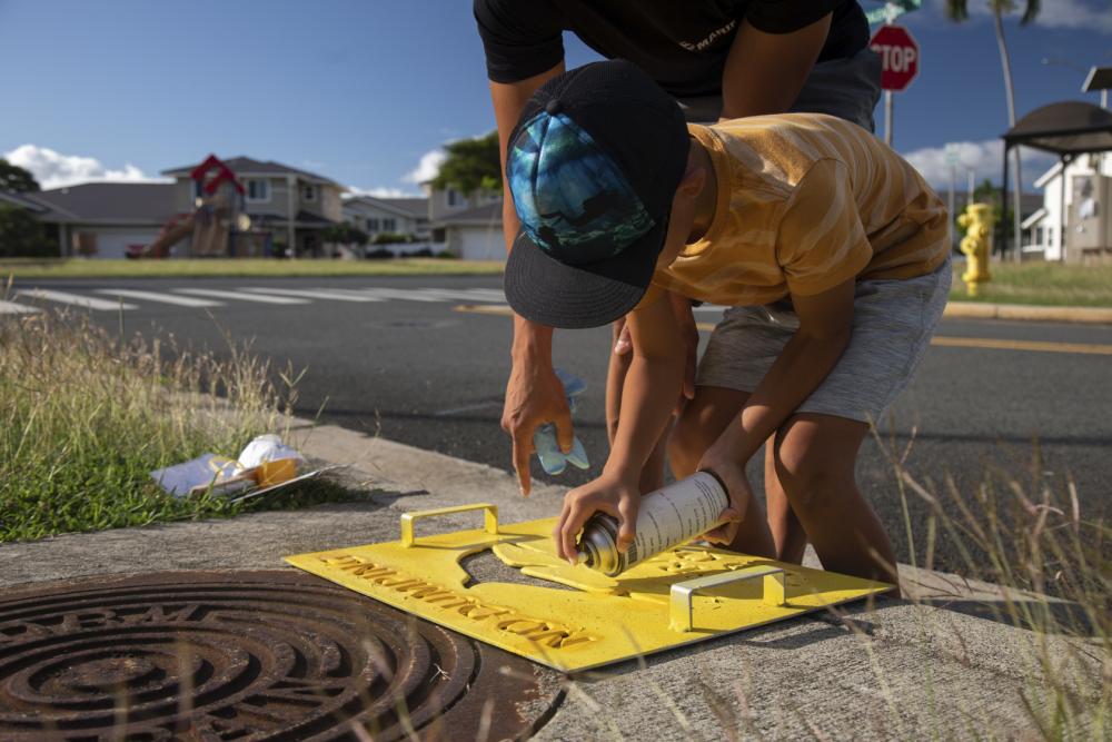 A volunteer applies a “No Dumping” sign during Operation Clean Water Ohana, Marine Corps Base Hawaii, Jan. 3, 2023.
