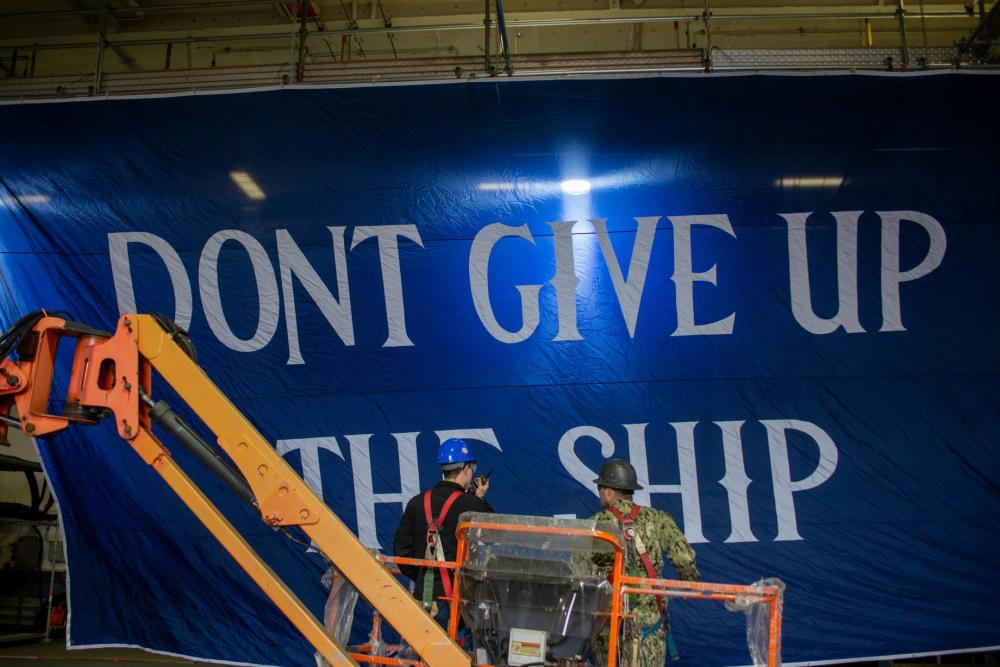 USS Ronald Reagan (CVN 76) Sailors hang banner in the hangar bay