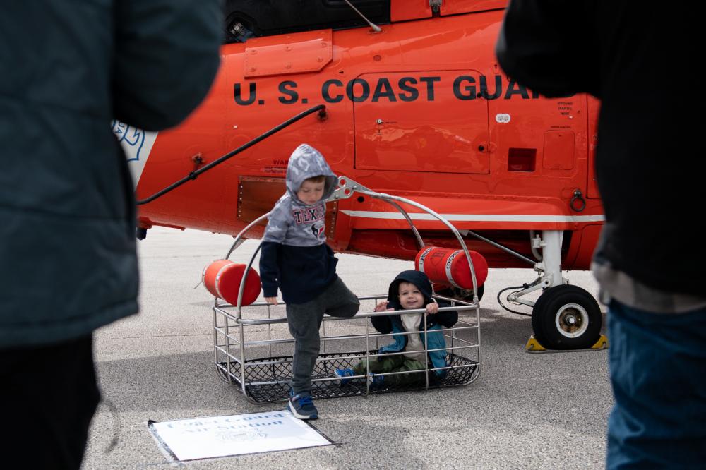 Members of the public pose for a photo in an MH-65 Dolphin helicopter rescue basket during Sector Houston-Galveston’s Community Day in Houston, Texas, Feb. 11, 2023. During the event, Coast Guard members from Sector Houston-Galveston and surrounding units displayed equipment and discussed various Coast Guard missions. (U.S. Coast Guard photo by Petty Officer 3rd Class Alejandro Rivera)