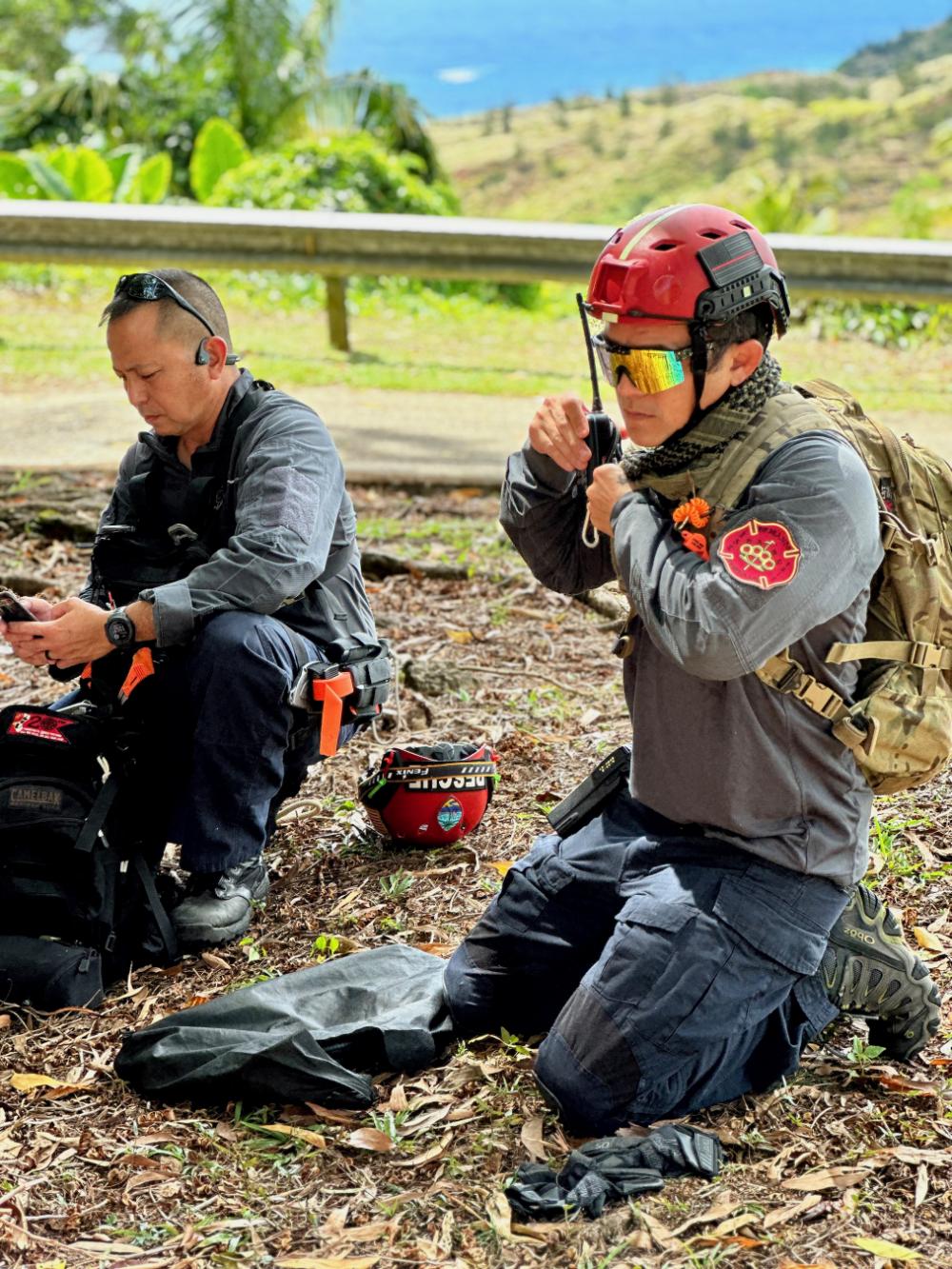 Members of the Guam Fire Department prepare to hike down from Sella Bay Overlook for rescue hoist training in Guam with a deployed MH-65 Dolphin helicopter crew from Hawaii on March 8, 2023. 